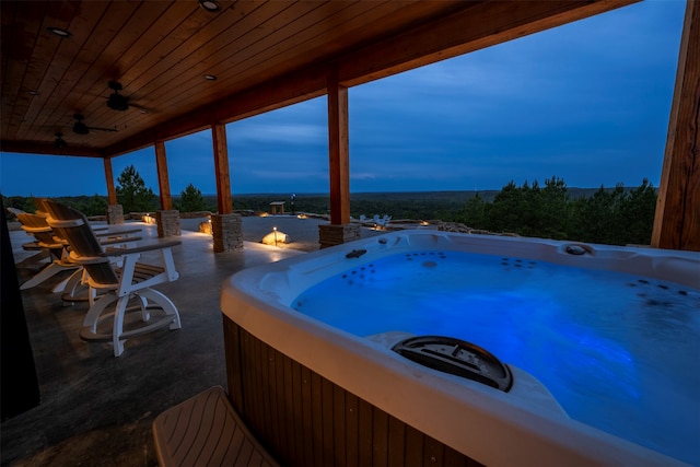 pool at dusk featuring ceiling fan and a hot tub