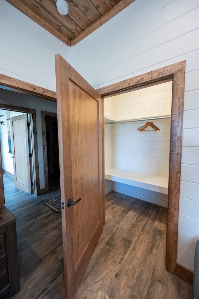 hall with dark wood-type flooring, wooden walls, and wooden ceiling