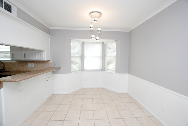 kitchen featuring kitchen peninsula, ornamental molding, light tile patterned floors, and an inviting chandelier