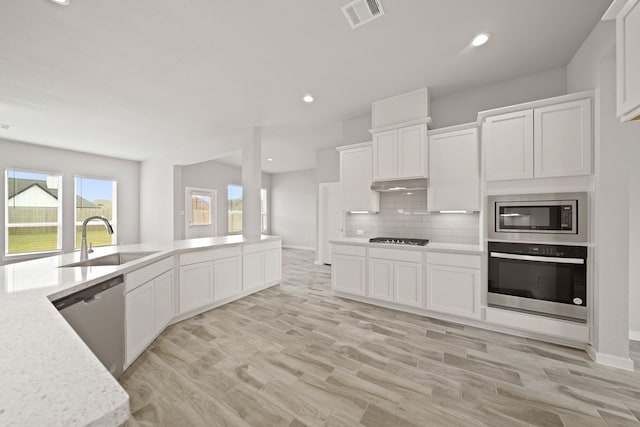 kitchen with white cabinets, sink, stainless steel appliances, and light hardwood / wood-style floors