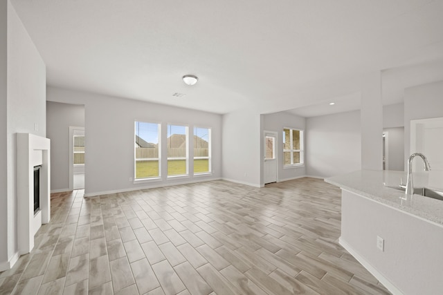 unfurnished living room with a wealth of natural light, sink, and light hardwood / wood-style floors