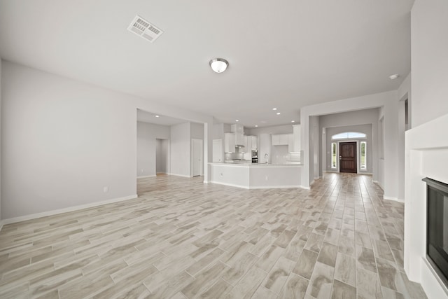 unfurnished living room with light hardwood / wood-style flooring and sink