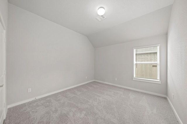 bonus room with vaulted ceiling and light colored carpet