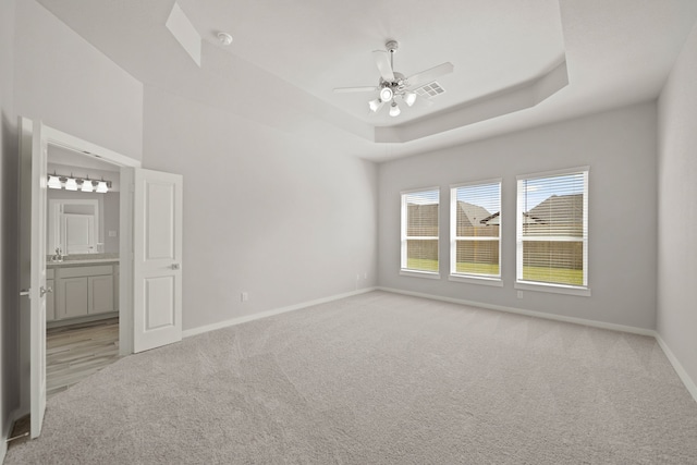 spare room featuring ceiling fan, a raised ceiling, and light carpet