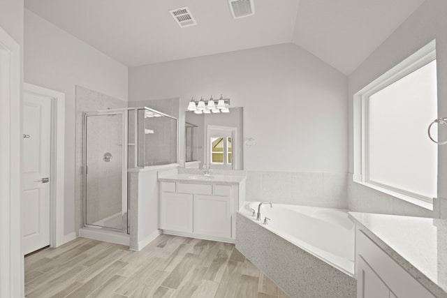 bathroom featuring vanity, vaulted ceiling, plus walk in shower, and wood-type flooring