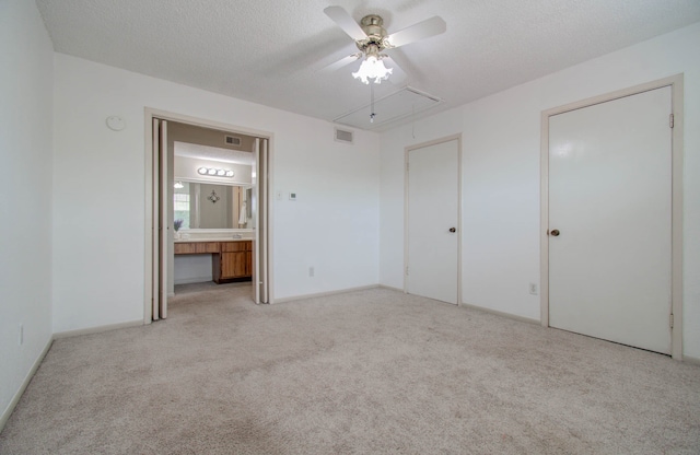 unfurnished bedroom with a textured ceiling, ceiling fan, light carpet, and ensuite bathroom