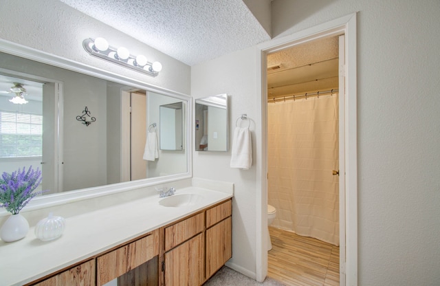 bathroom with walk in shower, toilet, wood-type flooring, vanity, and a textured ceiling