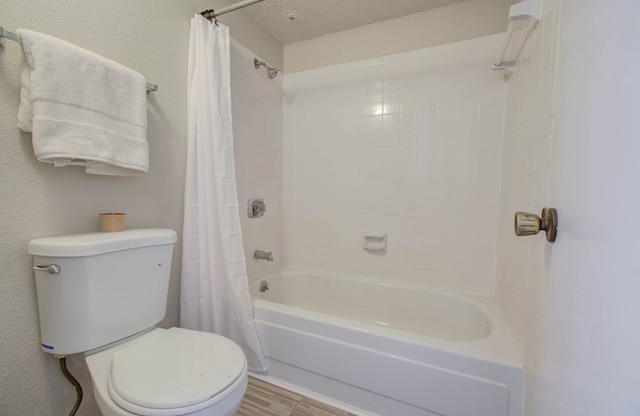 bathroom featuring toilet, hardwood / wood-style floors, shower / bath combo with shower curtain, and a textured ceiling