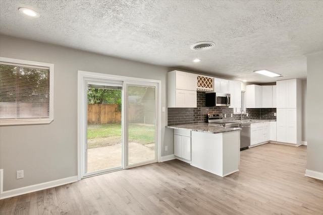 kitchen featuring appliances with stainless steel finishes, plenty of natural light, and white cabinetry