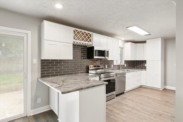 kitchen featuring stainless steel appliances, white cabinetry, and light hardwood / wood-style flooring