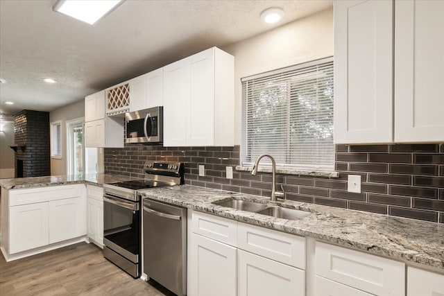 kitchen with white cabinetry, light hardwood / wood-style flooring, a textured ceiling, sink, and appliances with stainless steel finishes