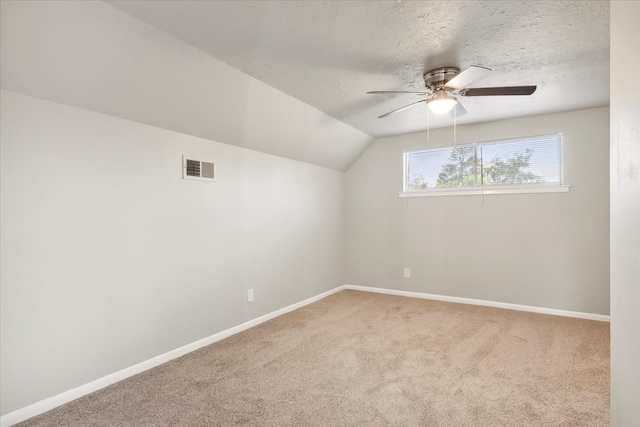 additional living space with lofted ceiling, light colored carpet, ceiling fan, and a textured ceiling