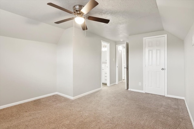 additional living space with a textured ceiling, light colored carpet, ceiling fan, and vaulted ceiling