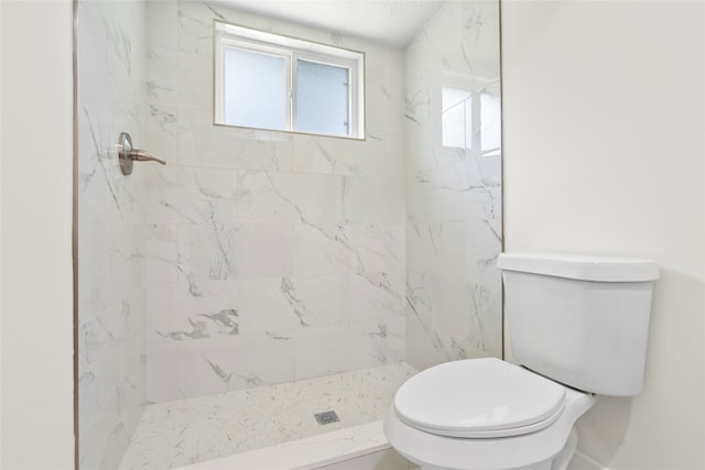 bathroom featuring toilet and a tile shower