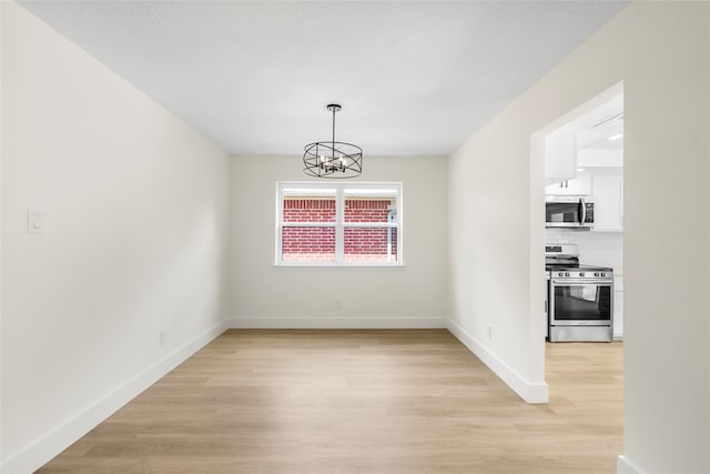 unfurnished dining area with a chandelier and light hardwood / wood-style floors