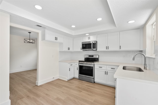 kitchen with light wood-type flooring, appliances with stainless steel finishes, sink, and white cabinets