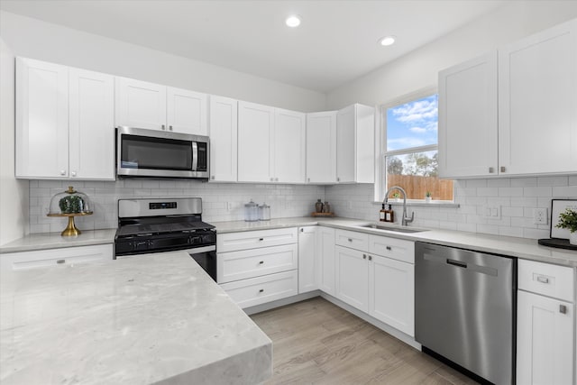 kitchen with white cabinets, appliances with stainless steel finishes, light hardwood / wood-style flooring, and sink