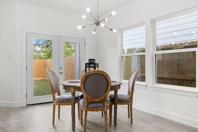 dining room with french doors, light wood-type flooring, and an inviting chandelier