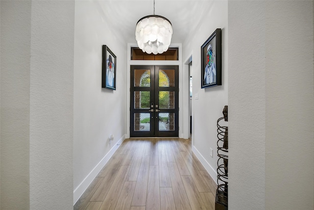 entryway featuring french doors, an inviting chandelier, and light hardwood / wood-style flooring