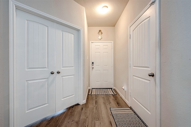 hallway featuring light wood-type flooring and a textured ceiling