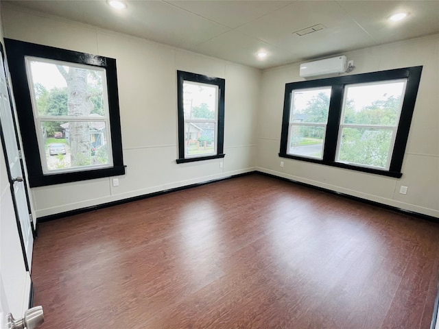 unfurnished room with plenty of natural light, dark hardwood / wood-style floors, and a wall mounted AC