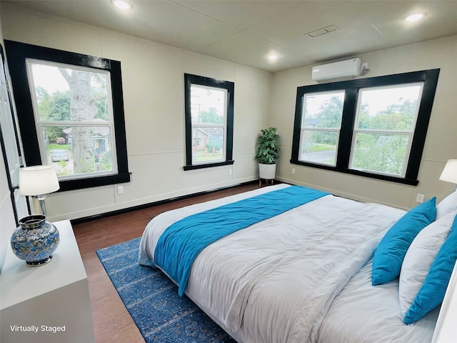 bedroom with dark hardwood / wood-style floors, an AC wall unit, and multiple windows