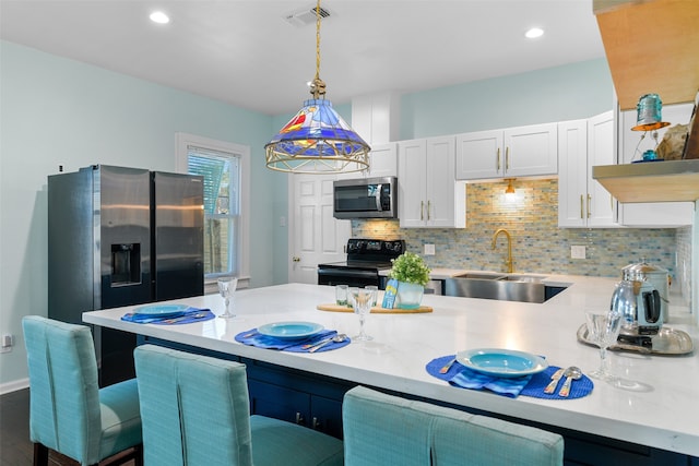 kitchen with a breakfast bar area, appliances with stainless steel finishes, hanging light fixtures, sink, and white cabinetry