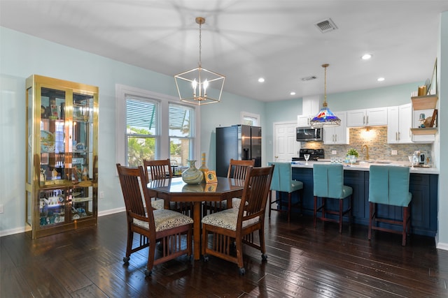 dining space featuring dark wood-type flooring, a chandelier, and sink