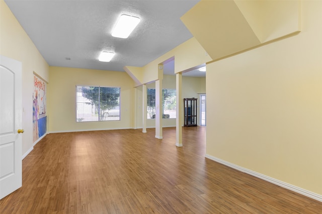 unfurnished living room with dark wood-type flooring, decorative columns, and a textured ceiling