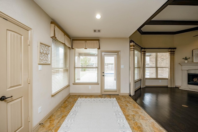 doorway with visible vents, wood finished floors, a high end fireplace, and baseboards