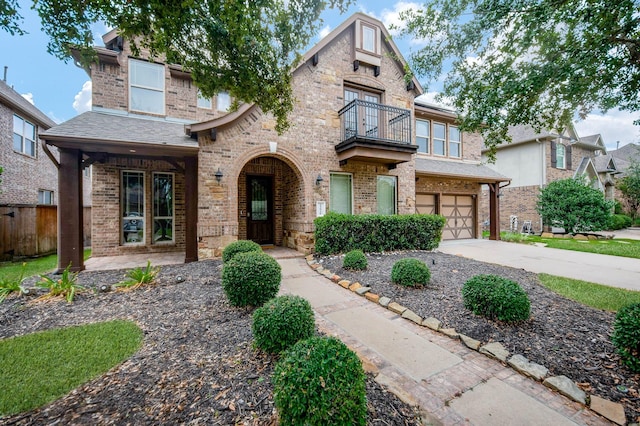 view of front of house with brick siding, a shingled roof, concrete driveway, an attached garage, and a balcony