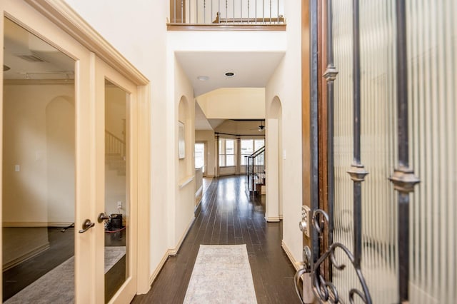 hall with arched walkways, visible vents, baseboards, french doors, and dark wood finished floors