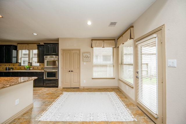 kitchen featuring stainless steel double oven, recessed lighting, dark cabinets, visible vents, and decorative backsplash