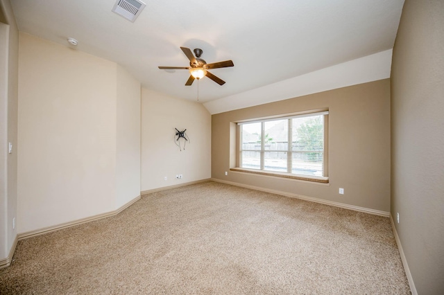 empty room featuring ceiling fan, carpet floors, visible vents, baseboards, and vaulted ceiling