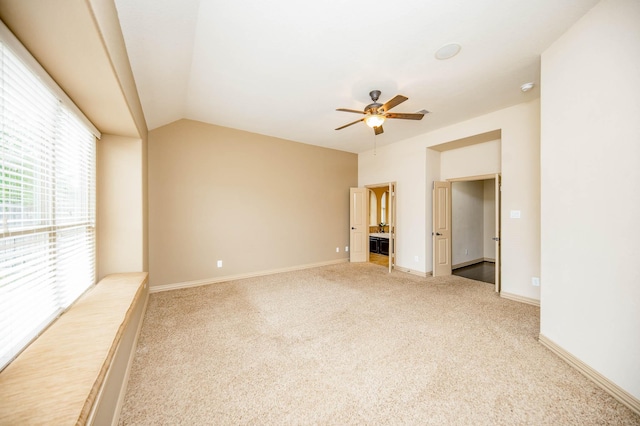 carpeted spare room with vaulted ceiling, ceiling fan, and baseboards