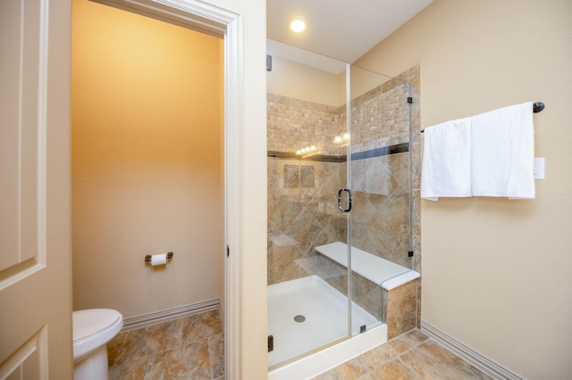 bathroom featuring toilet, a shower stall, and baseboards