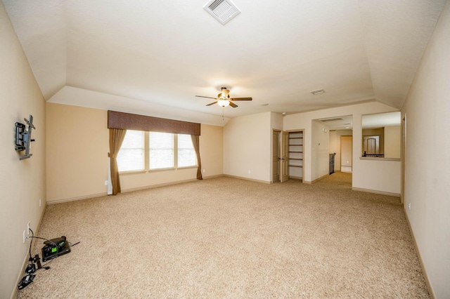 spare room with lofted ceiling, light colored carpet, visible vents, a ceiling fan, and baseboards