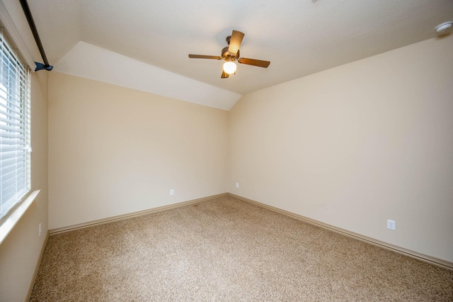 unfurnished room featuring carpet floors, vaulted ceiling, baseboards, and a ceiling fan