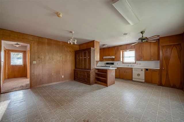 kitchen with ceiling fan with notable chandelier, white appliances, sink, kitchen peninsula, and wood walls