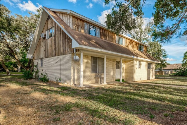 rear view of property featuring a lawn and a wall mounted air conditioner