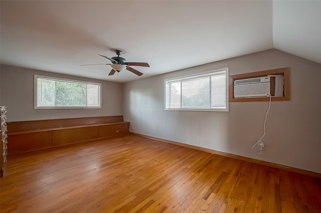 unfurnished room featuring vaulted ceiling, an AC wall unit, ceiling fan, and light hardwood / wood-style floors