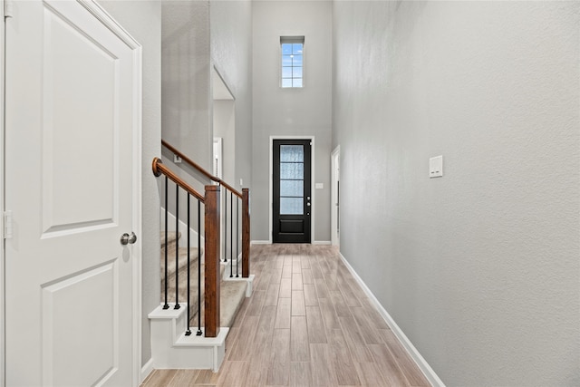 doorway with a towering ceiling, light hardwood / wood-style flooring, and a healthy amount of sunlight