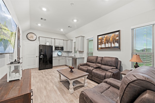 living room with sink, light hardwood / wood-style flooring, and vaulted ceiling