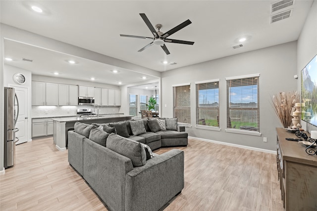 living room with light wood-type flooring, a healthy amount of sunlight, and ceiling fan