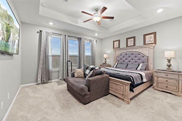 bedroom featuring light carpet, a tray ceiling, and ceiling fan