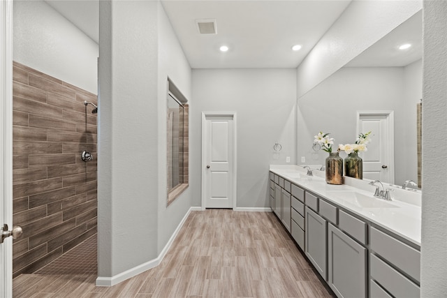 bathroom with vanity, hardwood / wood-style flooring, and tiled shower