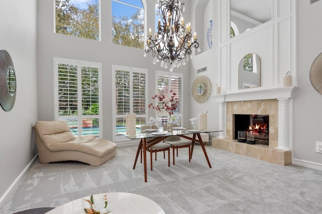 interior space with carpet flooring, a high ceiling, an inviting chandelier, and a fireplace