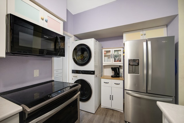 laundry area featuring hardwood / wood-style flooring and stacked washer / drying machine