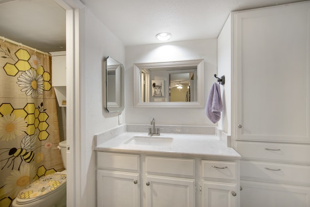 bathroom with a textured ceiling, vanity, and toilet