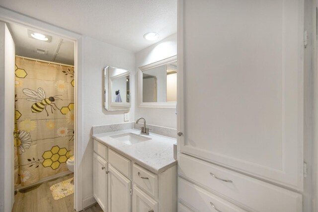 bathroom featuring toilet, hardwood / wood-style flooring, a textured ceiling, and vanity